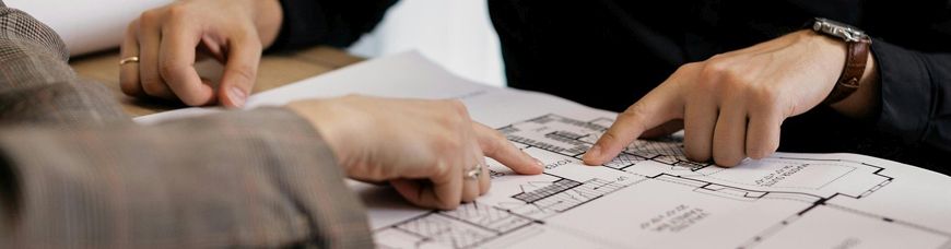 Vier Hände mit Hausbauplan auf Tisch